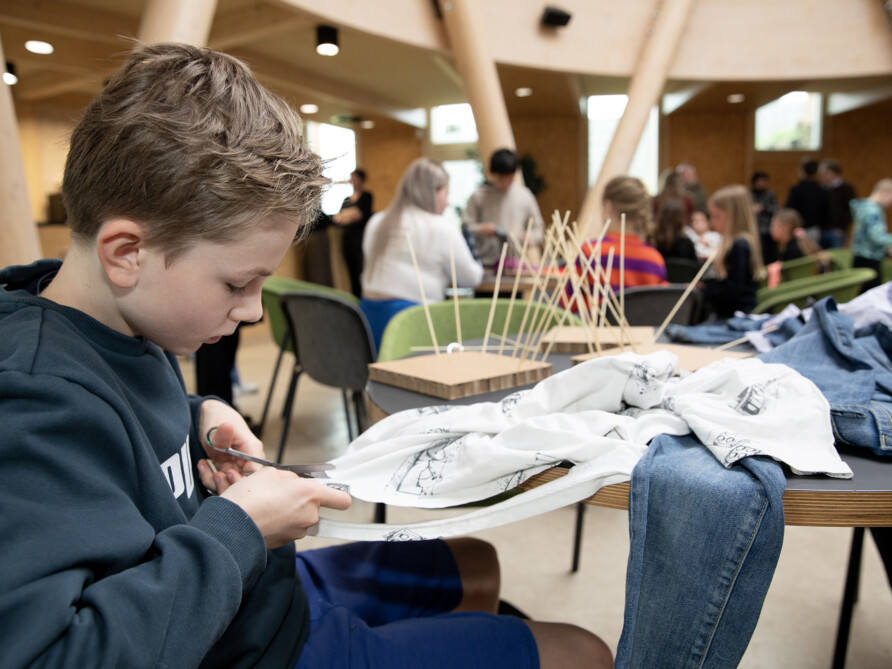 Leerling van OBS de Buttinga knipt strookjes voor zijn kunstwerk